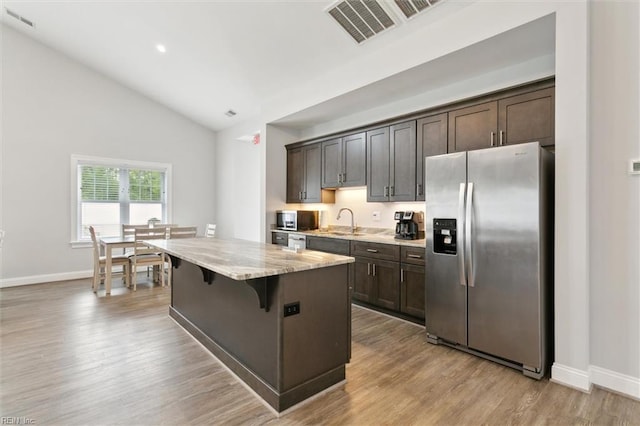 kitchen featuring visible vents, a sink, lofted ceiling, a breakfast bar, and stainless steel appliances