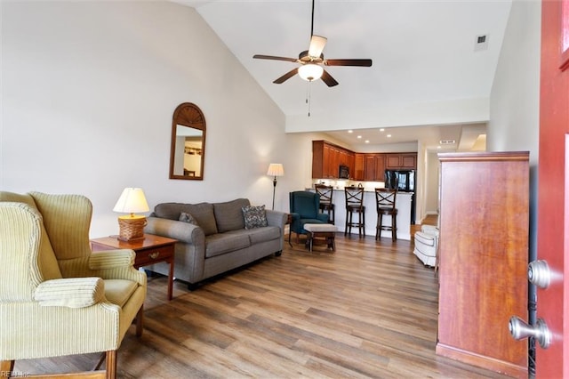 living room with ceiling fan, visible vents, wood finished floors, and high vaulted ceiling