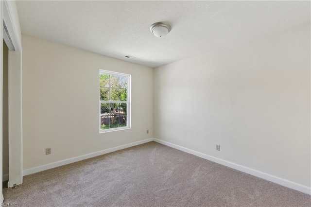 unfurnished room with carpet, visible vents, and baseboards