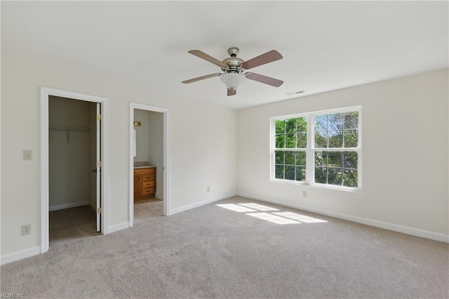 unfurnished bedroom with a closet, carpet flooring, baseboards, and a spacious closet