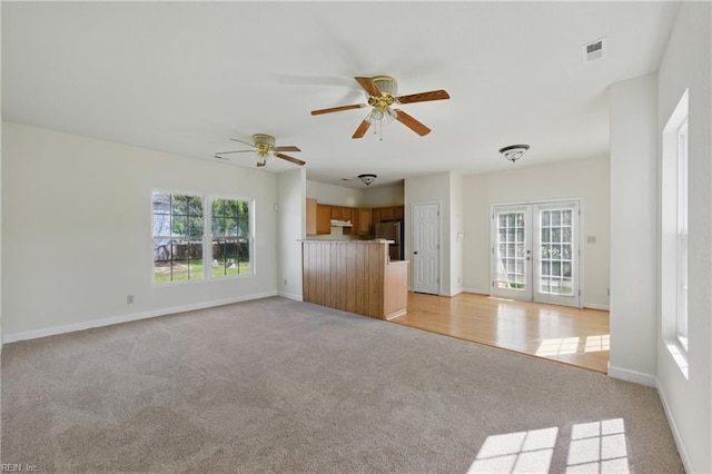 unfurnished living room featuring baseboards, visible vents, light carpet, and ceiling fan