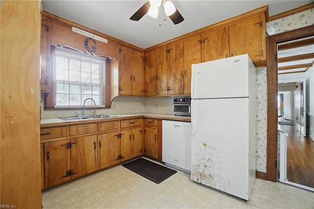 kitchen with light floors, white appliances, brown cabinets, ceiling fan, and a sink