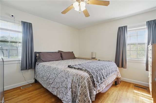 bedroom with wood finished floors, visible vents, ceiling fan, and baseboards