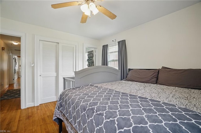 bedroom with hardwood / wood-style floors, baseboards, a ceiling fan, and a closet