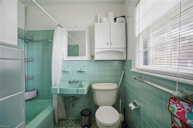 bathroom featuring shower / bathtub combination with curtain, toilet, wainscoting, and tile walls