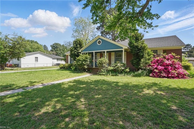 view of front of home featuring a front lawn, fence, covered porch, and brick siding