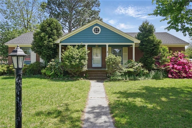 view of front of home with a porch, a front lawn, and brick siding