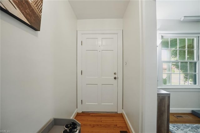doorway with wood finished floors, visible vents, and baseboards