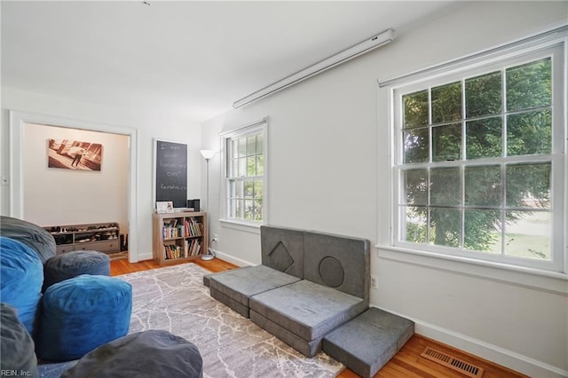 living room featuring baseboards, visible vents, wood finished floors, and a healthy amount of sunlight