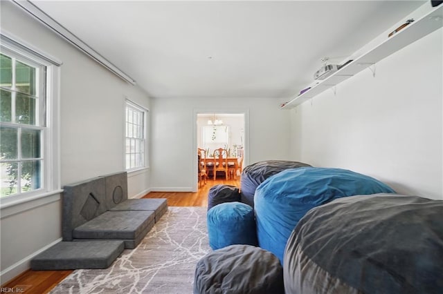 living room featuring wood finished floors, a notable chandelier, and baseboards