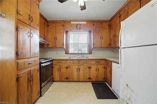 kitchen with a sink, under cabinet range hood, brown cabinetry, a ceiling fan, and white appliances