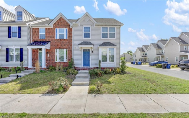 view of property featuring brick siding, a residential view, and a front yard
