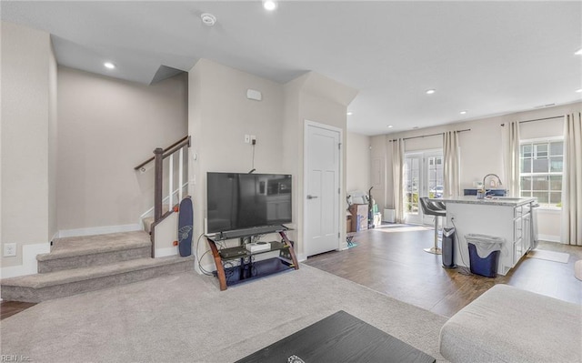 carpeted living room with a sink, recessed lighting, and stairs