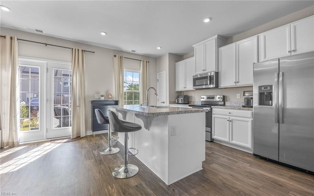 kitchen with a sink, appliances with stainless steel finishes, a breakfast bar area, and dark wood-style flooring
