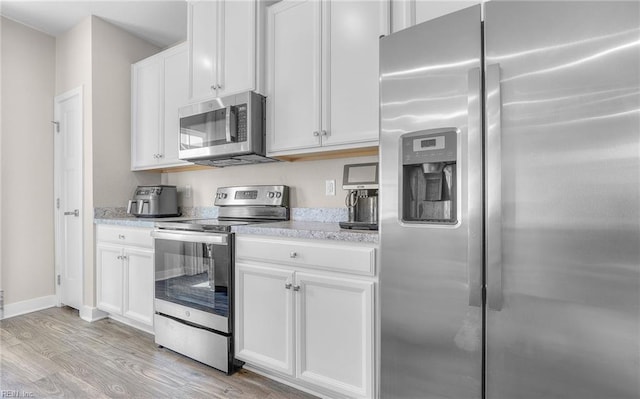 kitchen with white cabinetry, appliances with stainless steel finishes, and light wood finished floors