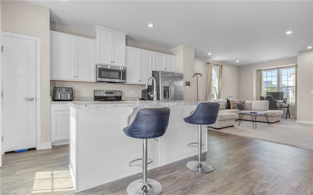 kitchen with appliances with stainless steel finishes, recessed lighting, white cabinetry, and open floor plan