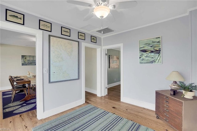 interior space with baseboards, visible vents, ornamental molding, and light wood-style flooring