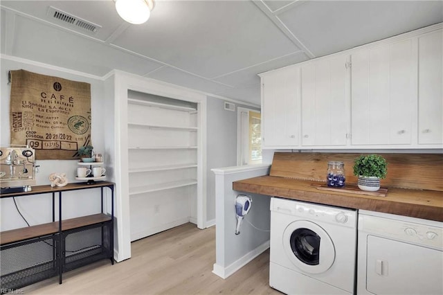 washroom with visible vents, light wood-style floors, baseboards, and separate washer and dryer