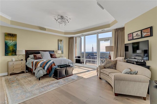 bedroom with ornamental molding, access to exterior, baseboards, a raised ceiling, and light wood-style flooring
