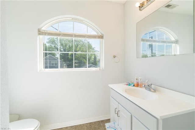 half bath featuring visible vents, baseboards, tile patterned floors, vanity, and toilet