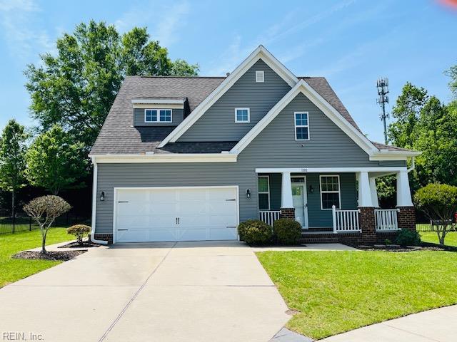 craftsman-style house with a shingled roof, an attached garage, a front lawn, covered porch, and driveway
