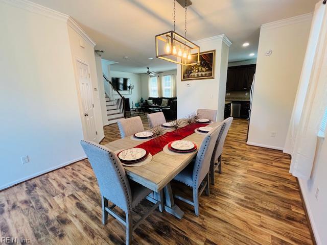 dining space featuring a ceiling fan, crown molding, wood finished floors, stairway, and baseboards