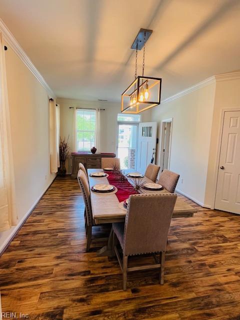 dining space with crown molding, dark wood finished floors, and an inviting chandelier
