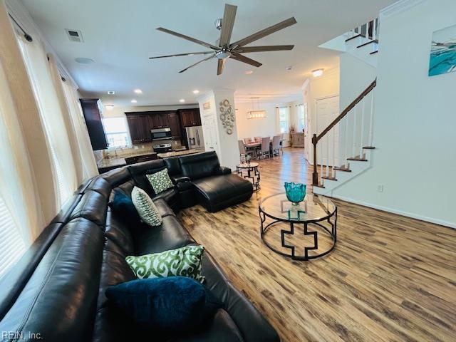 living room with ceiling fan, visible vents, a wealth of natural light, and stairway