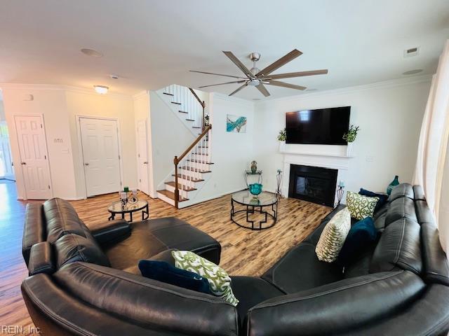living room with ornamental molding, stairs, ceiling fan, and wood finished floors