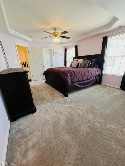 bedroom featuring ceiling fan, light carpet, and a tray ceiling