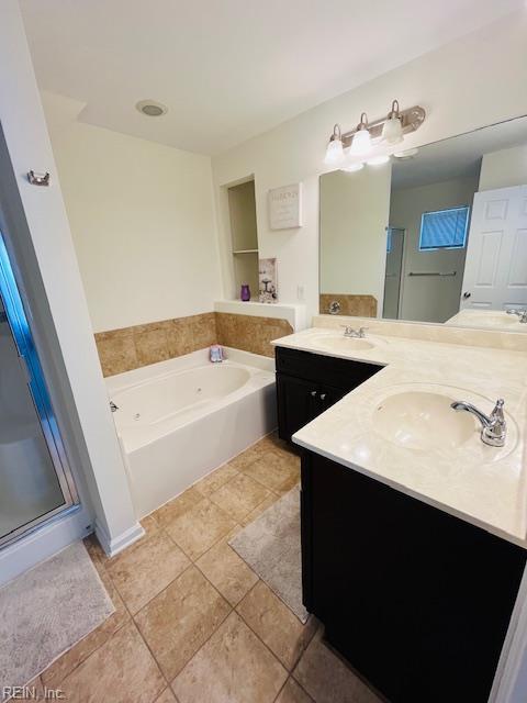 bathroom featuring double vanity, a sink, a bath, and a shower stall