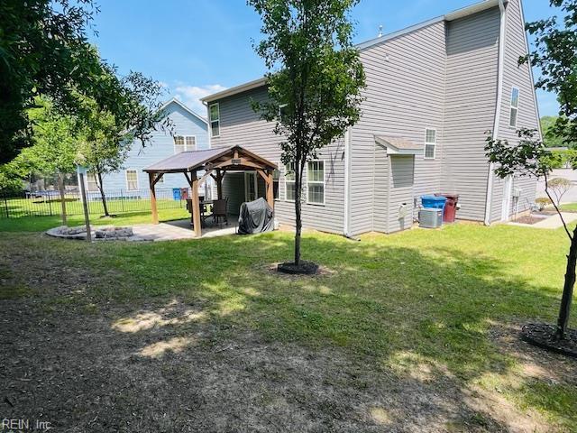 rear view of property featuring a lawn, central AC, fence, a patio area, and a gazebo