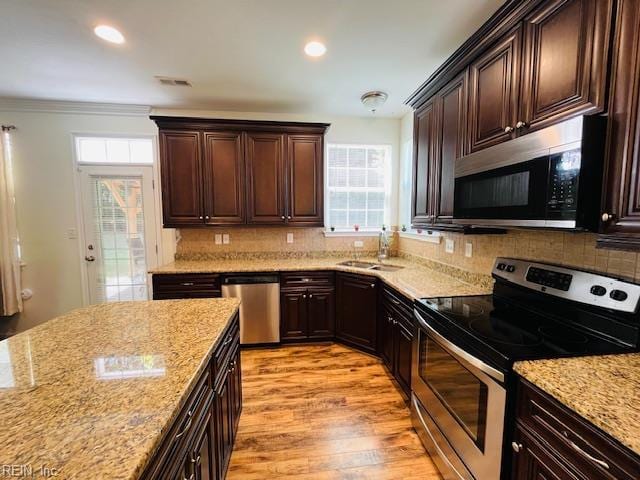 kitchen with visible vents, light wood-type flooring, light stone counters, a sink, and appliances with stainless steel finishes