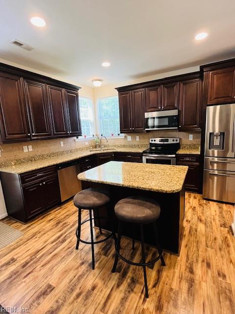 kitchen with decorative backsplash, a breakfast bar area, visible vents, appliances with stainless steel finishes, and a sink