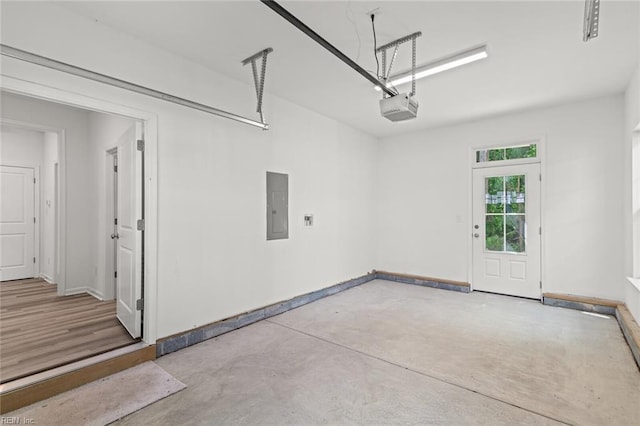 garage with baseboards, a garage door opener, and electric panel