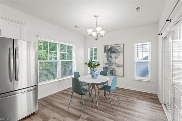 dining room featuring baseboards, plenty of natural light, light wood-type flooring, and a chandelier