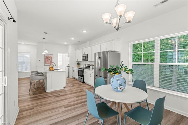 dining area with an inviting chandelier, baseboards, light wood-style flooring, and visible vents