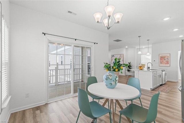dining space featuring visible vents, light wood-style floors, baseboards, and an inviting chandelier