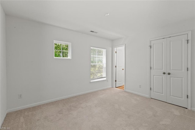 unfurnished bedroom featuring carpet flooring, baseboards, visible vents, and a closet