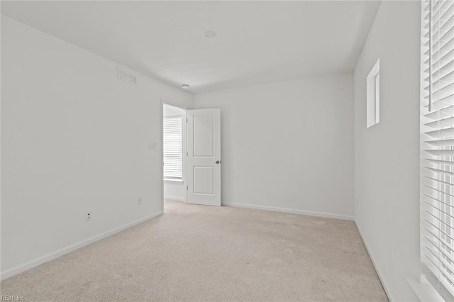 unfurnished room with baseboards, plenty of natural light, visible vents, and light colored carpet