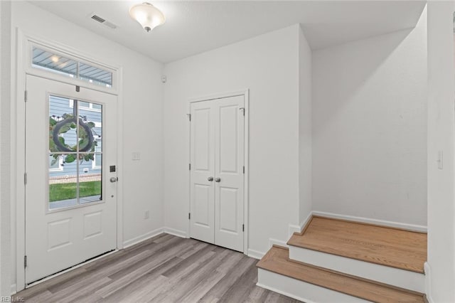 entryway featuring stairs, baseboards, visible vents, and wood finished floors