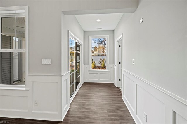 doorway featuring wainscoting, dark wood-style flooring, and a decorative wall