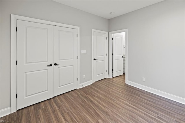 unfurnished bedroom with a closet, wood finished floors, and baseboards