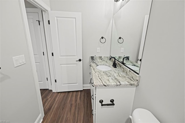 bathroom with baseboards, wood finished floors, toilet, and vanity