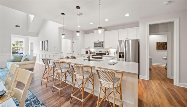 kitchen with a sink, appliances with stainless steel finishes, wood finished floors, and visible vents