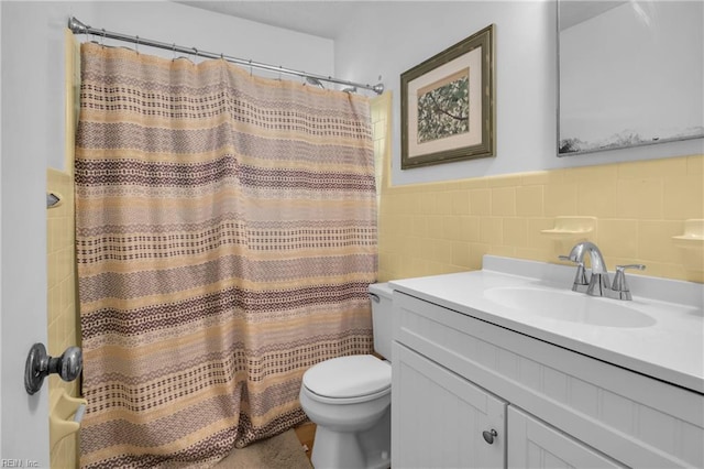 bathroom with tile walls, shower / bath combo, vanity, toilet, and wainscoting