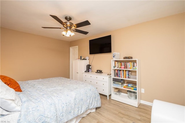 bedroom with baseboards, ceiling fan, and light wood-style flooring