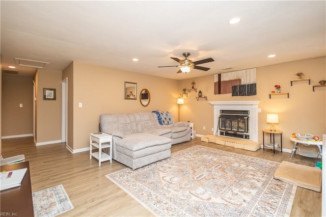 living room with a ceiling fan, baseboards, and light wood-type flooring
