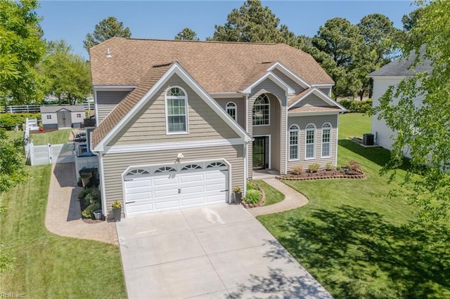 traditional-style house with an attached garage, a shingled roof, a front lawn, concrete driveway, and central air condition unit