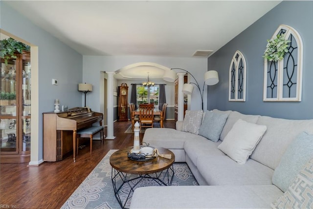 living room featuring visible vents, decorative columns, wood finished floors, a chandelier, and arched walkways